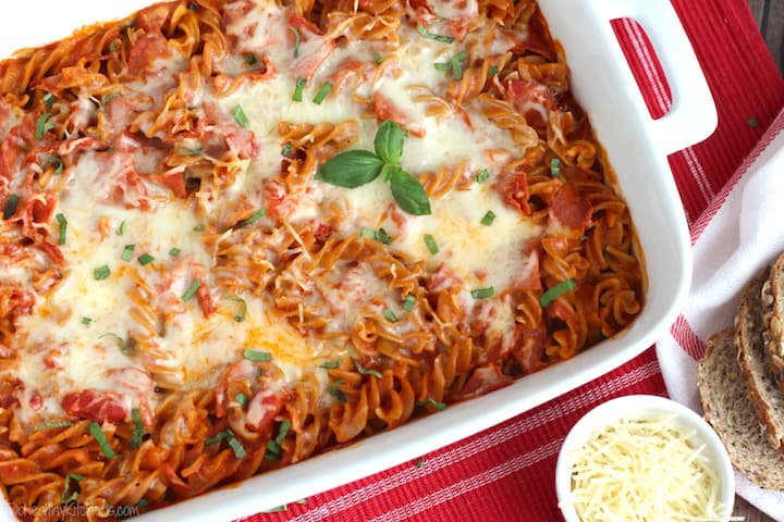 white casserole dish with the pizza pasta bake on a red tablecloth