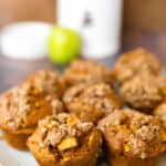 a plate of pumpkin apple muffins with an apple in the background