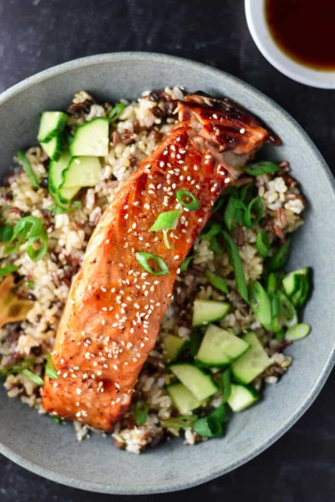 sweet chili salmon in a bowl with rice, topped with scallions.