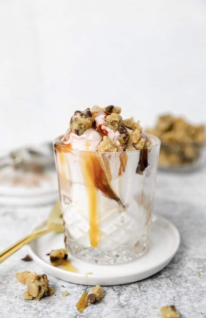 ice cream in a glass topped with the cookie dough, caramel sauce, and chocolate sauce.