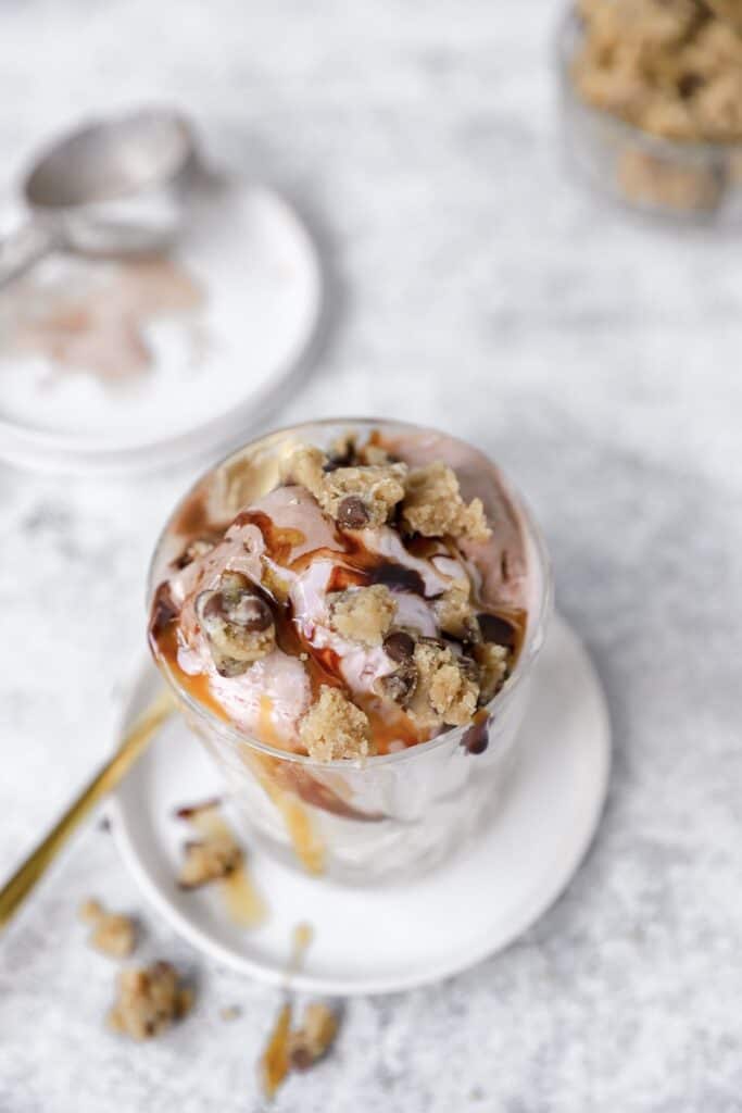 overhead shot of the cookie dough topped on the ice cream sundae with a gold spoon