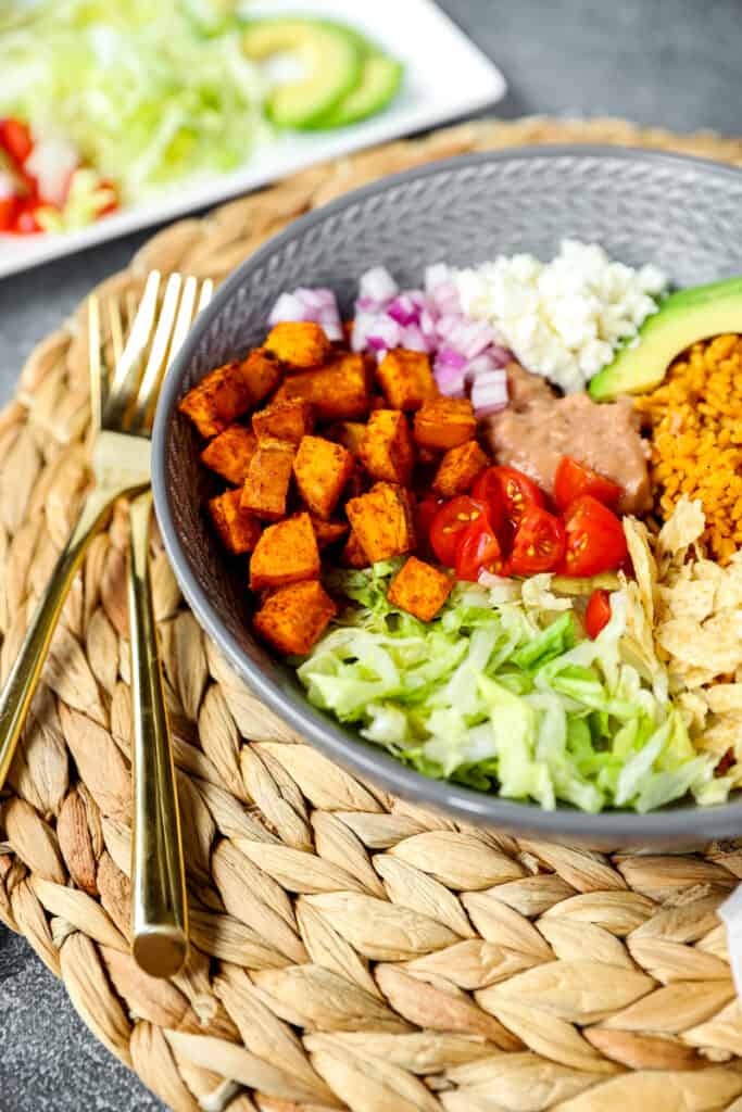 photos of the taco seasoned sweet potato in a grey bowl with other taco fixings. Two gold forks to the left side.