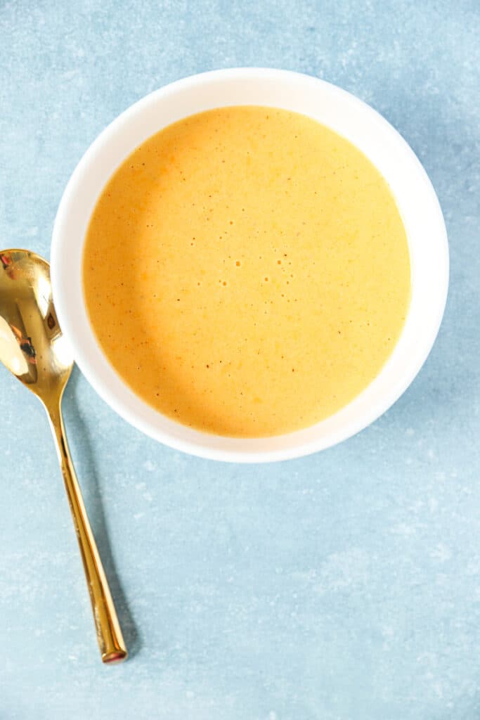 overhead shot of beer cheese in a white bowl with a gold spoon