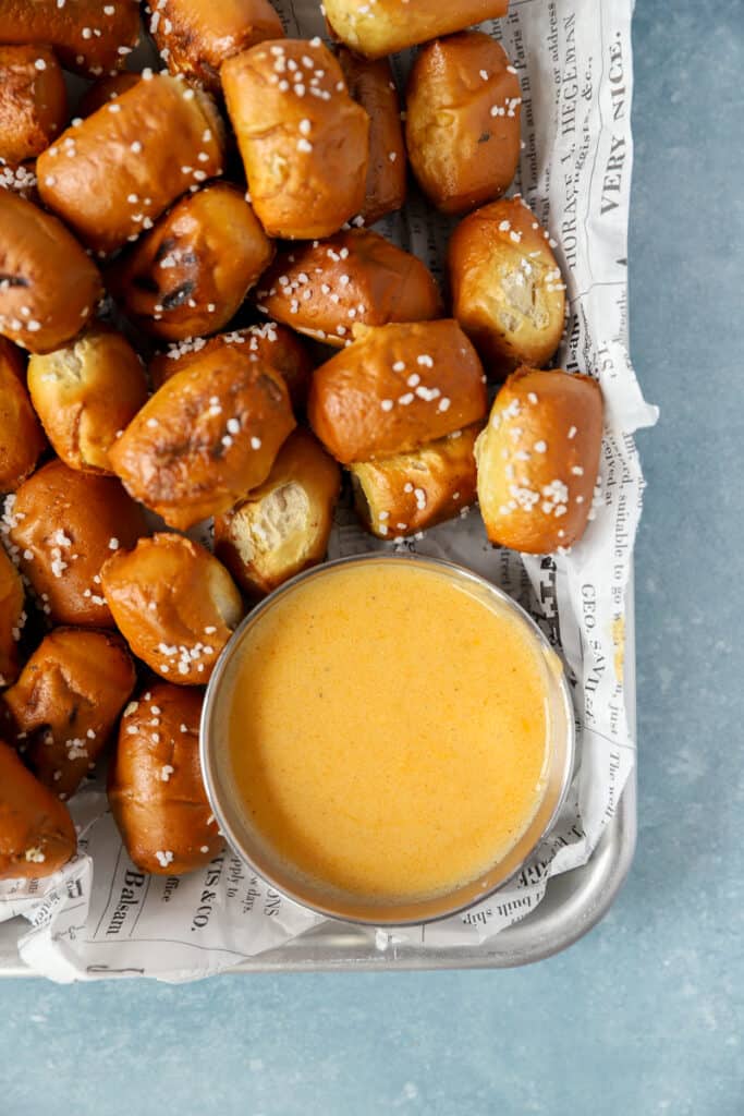 overhead shot of beer cheese sauce in a small silver dish with pretzel bites