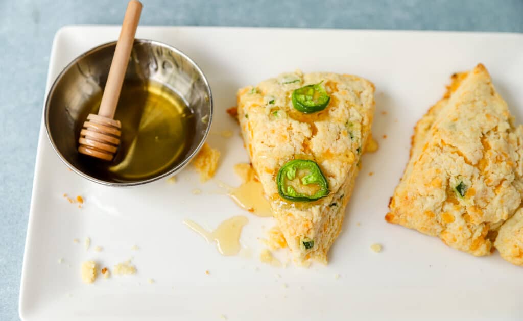 the scones on a white plate with a dish of honey