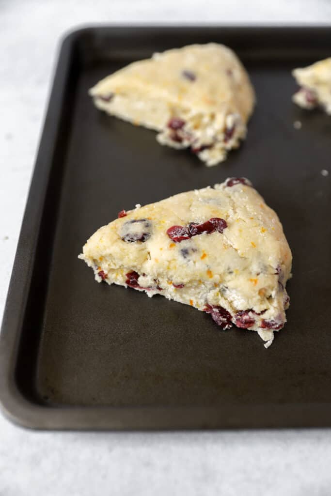 an unbaked scone on the dark nonstick baking sheet.