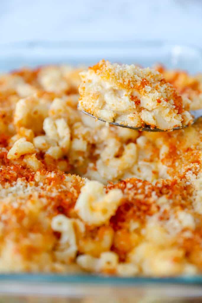 a large silver spoon scooping the mac and cheese from the casserole dish