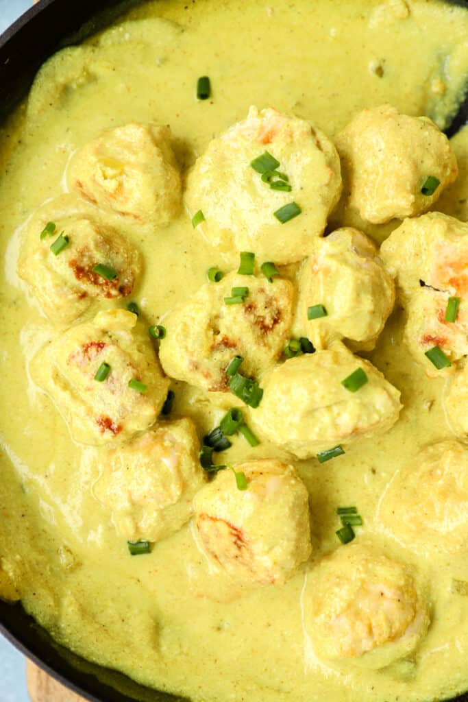 overhead photo of the creamy curry sauce chicken meatballs topped with diced chives.