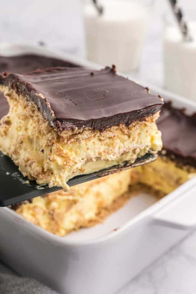 a spatula scooping a slice of eclair cake from the casserole dish