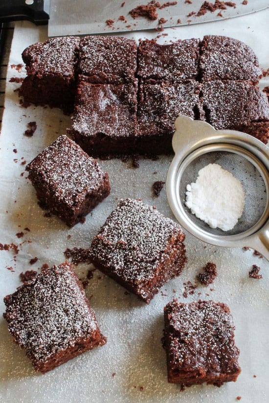 overhead photo of brownie squares with a sifter full of powdered sugar.