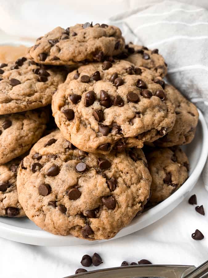 a white plate stacked with the chocolate chip cookies.