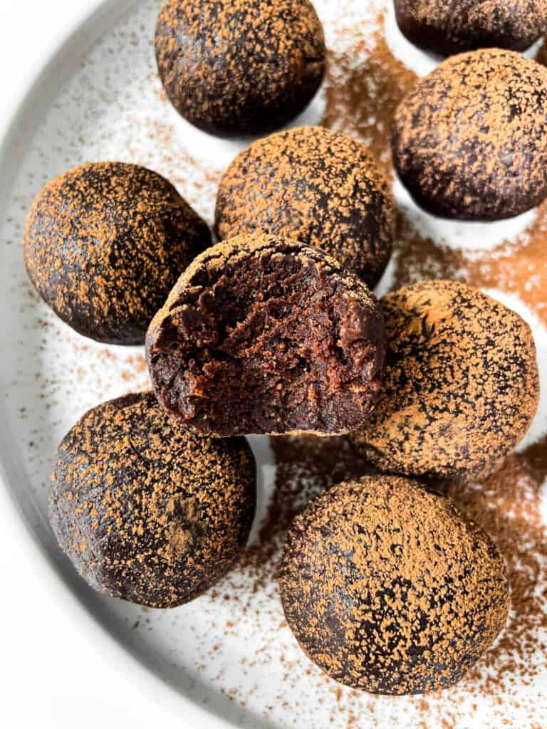 overhead photo of the plate of vegan brownie truffles with one having a bite taken out showing the interior texture.