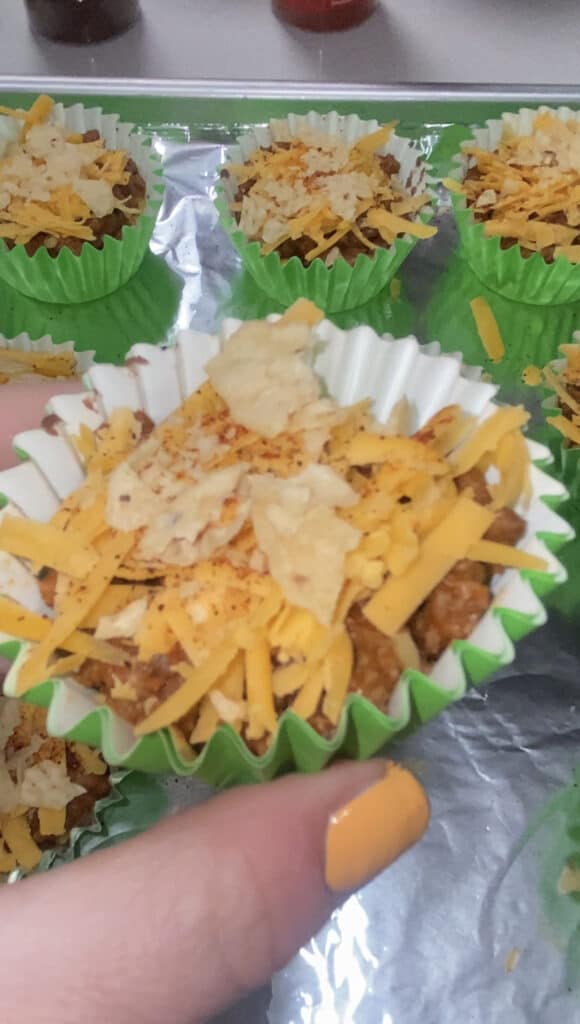 the mini taco bake casseroles on the baking sheet, and hand holding one of the casseroles close to the camera.