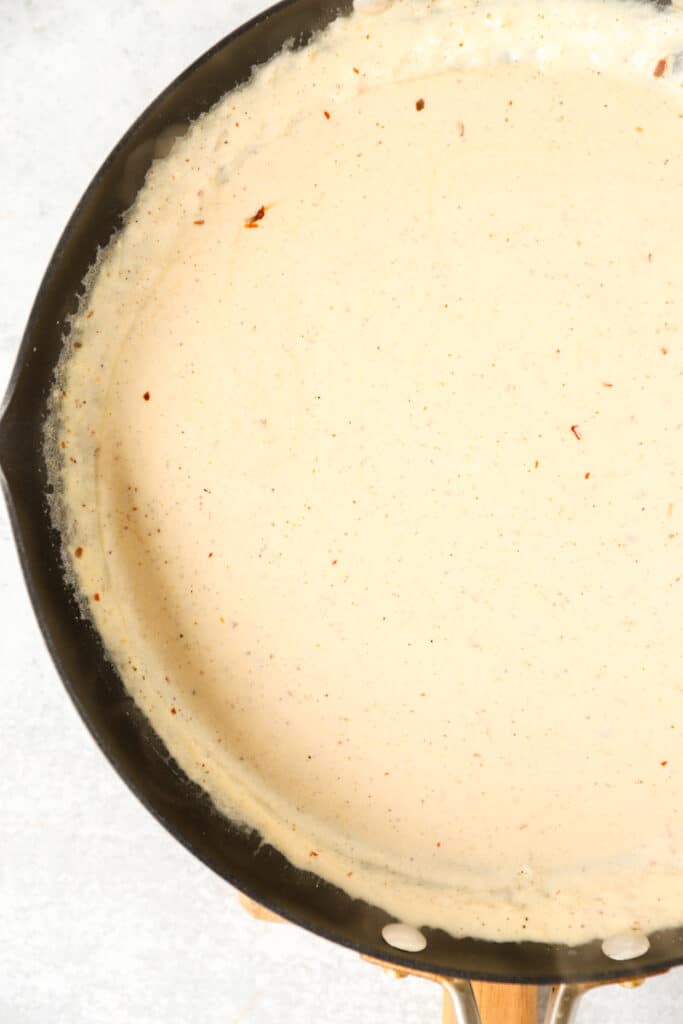 overhead photo of the cream sauce in a dark nonstick pan.