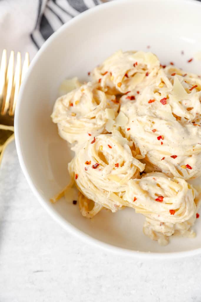 pasta noodle swirls of the spicy Alfredo in a white bowl.