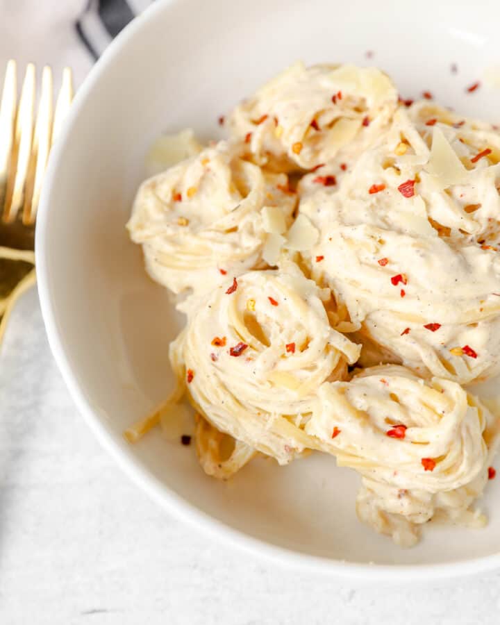 pasta noodle swirls of the spicy Alfredo in a white bowl.