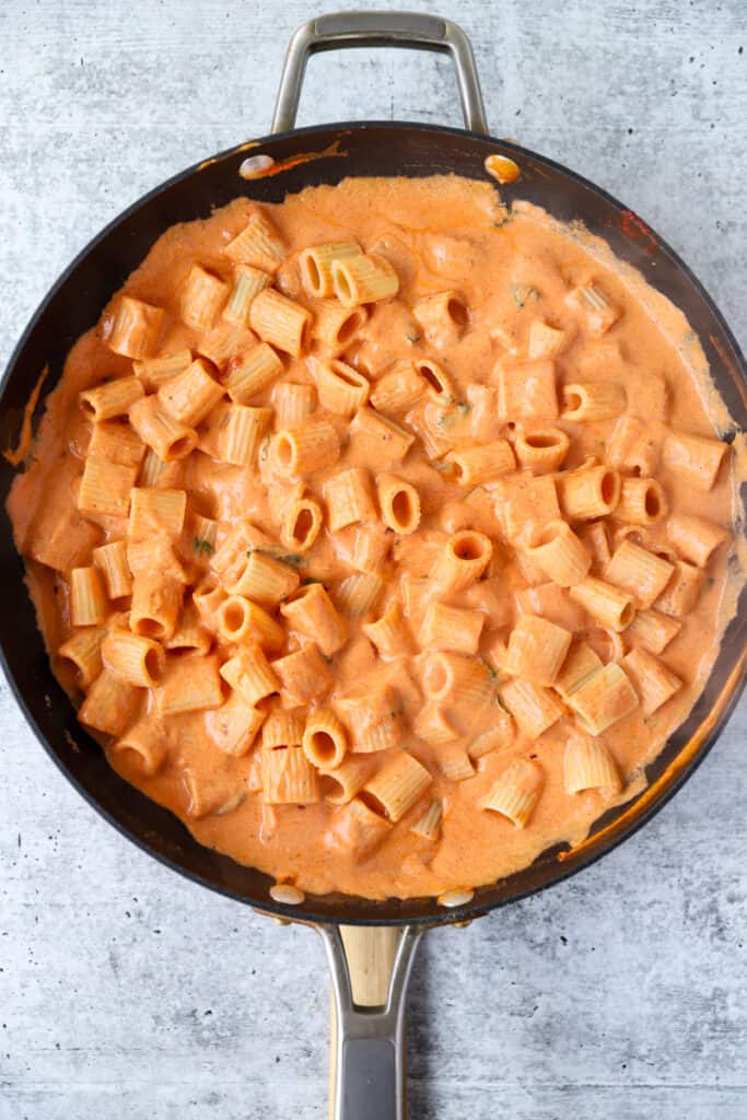 overhead photo of the spicy vodka sauce with rigatoni pasta in a black nonstick pan.