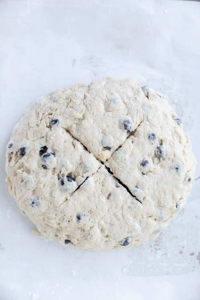 overhead photo of the raw unbaked loaf of soda bread with a "X" cut into the top.