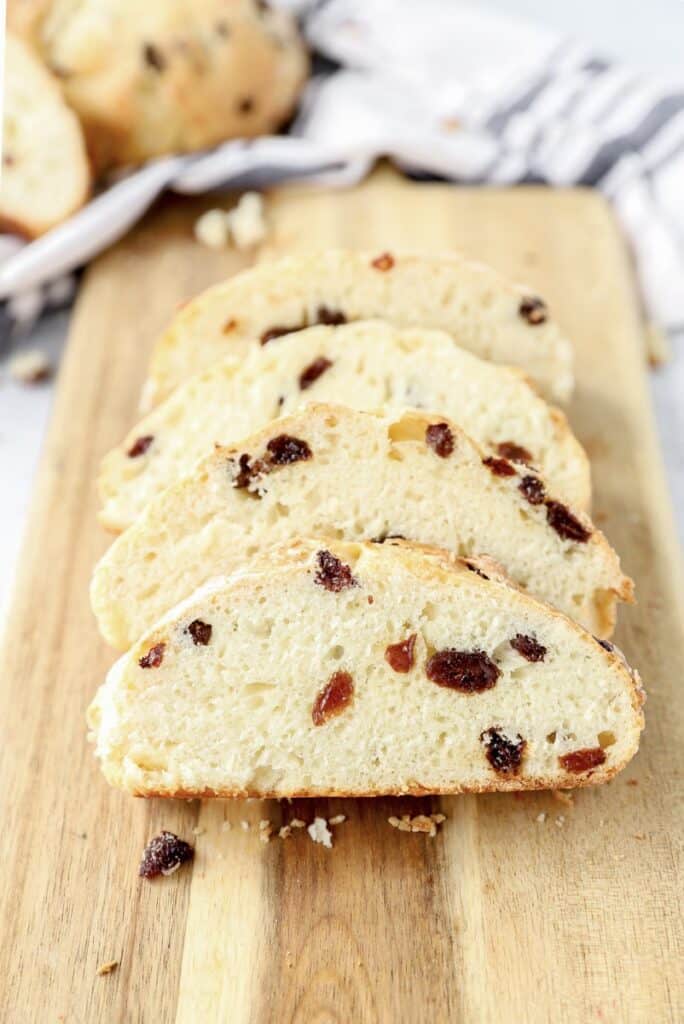 slices of the soda bread on a wood cutting board with a blue and white striped linen napkin in the back