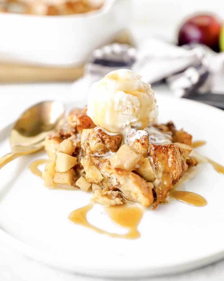 apple biscuit bread pudding on a white plate with ice cream on top.