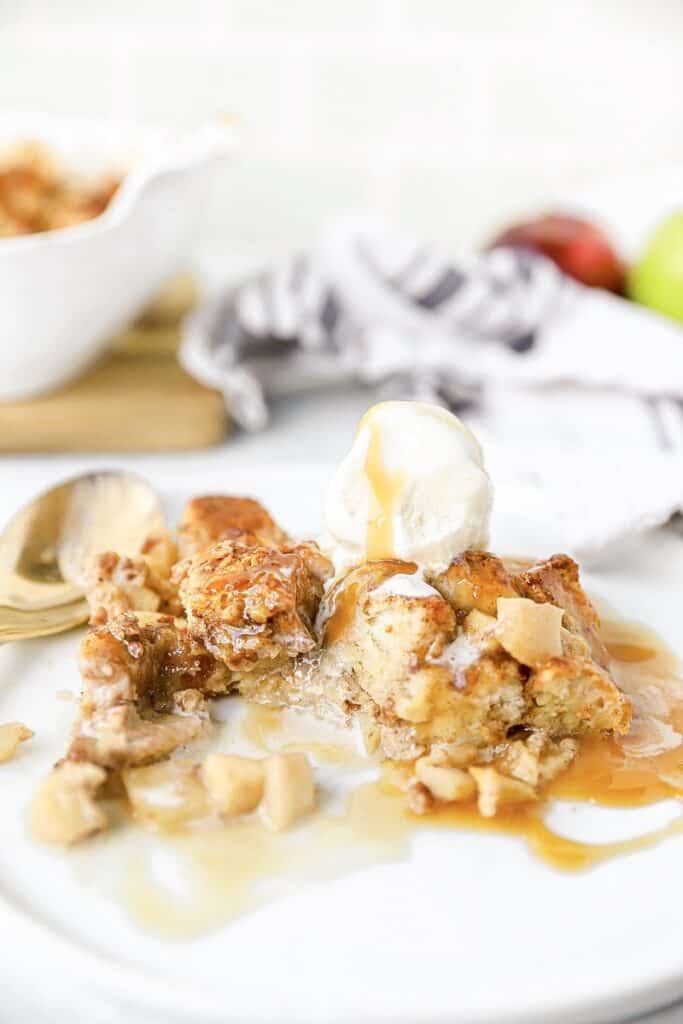 the bread pudding partially eaten topped with ice cream on a white plate.