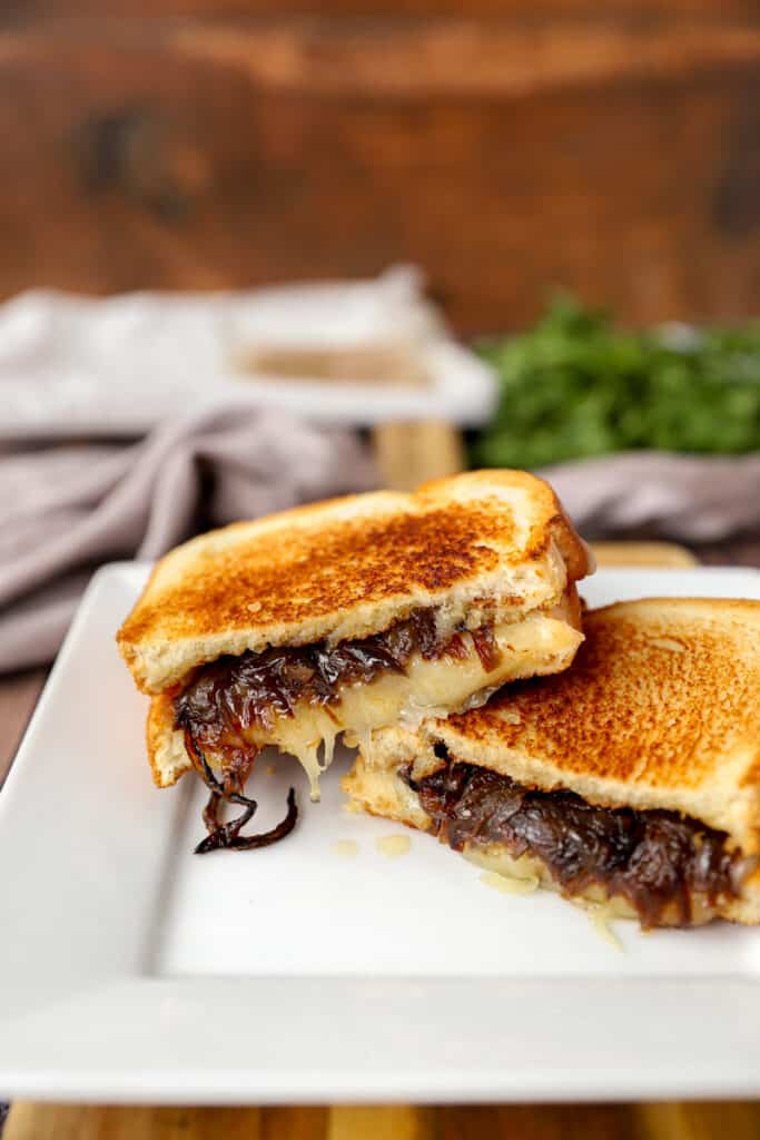 two slices of the grilled cheese stacked on a white plate.