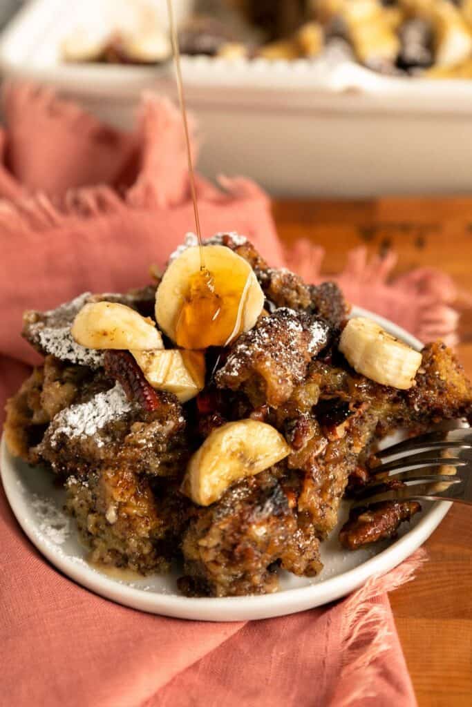 a stack of banana bread French toast being drizzled with syrup.