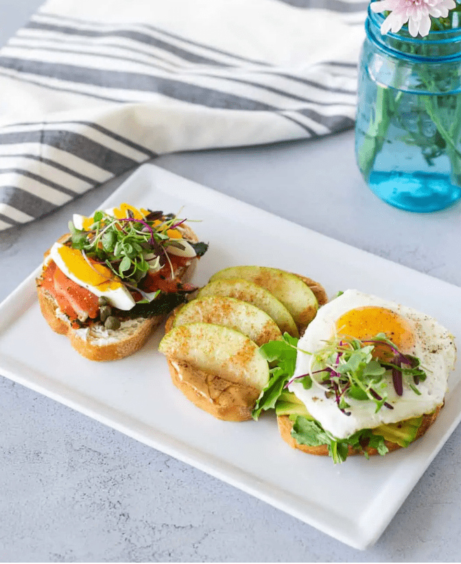 three brunch toasts on a white rectangle platter