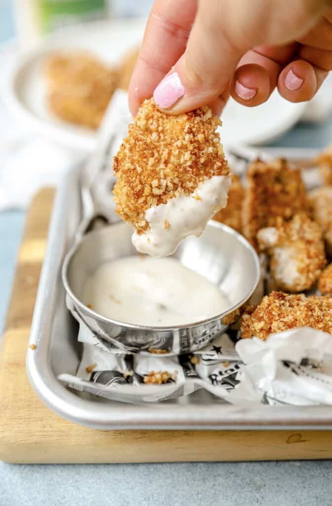 a hand dipping one of the spicy chicken nuggets into ranch.