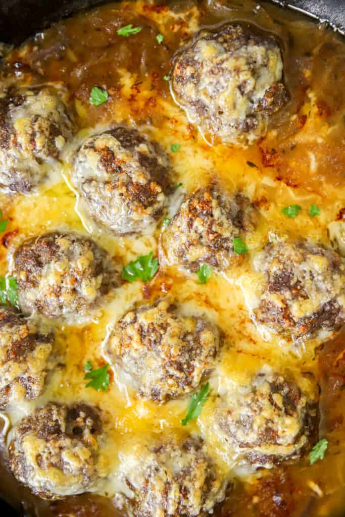 close overhead photo of the French onion meatballs in a cast iron skillet.