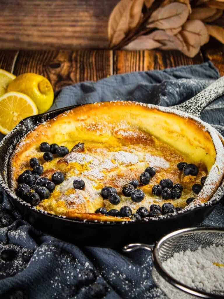 lemon Dutch baby topped with fresh blueberries in a cast iron skillet.