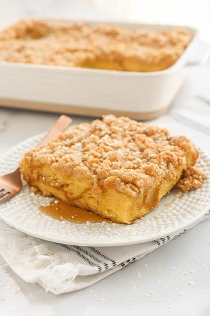 a slice of overnight French toast on a plate, the casserole dish in the back.