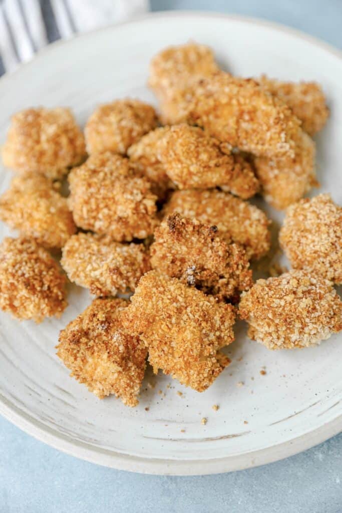 spicy chicken nuggets on a grey round plate.