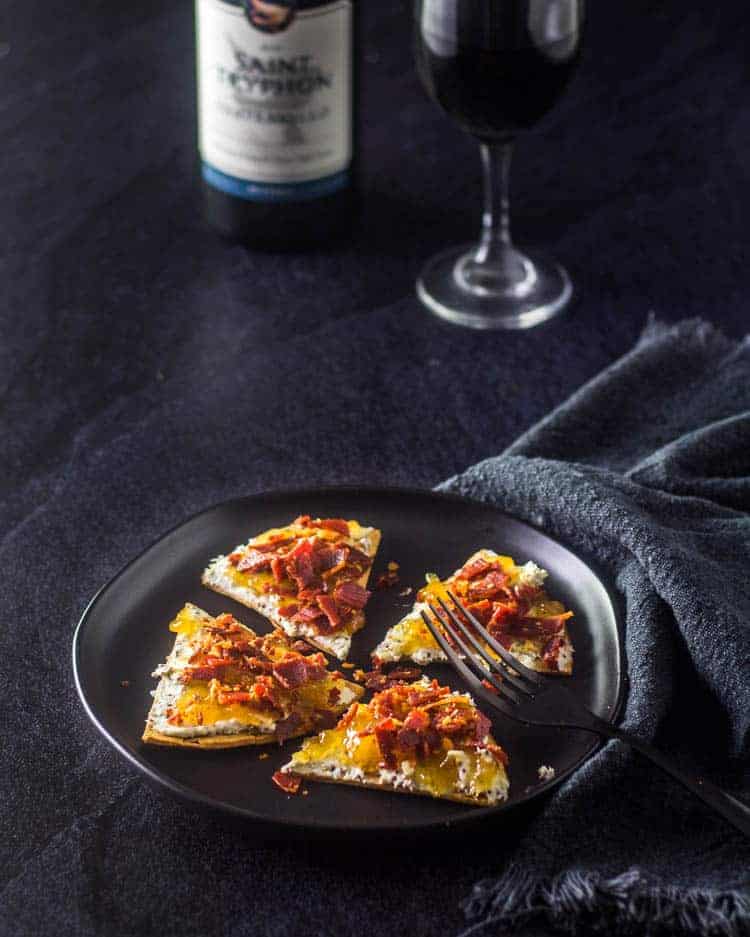 Fig and Prosciutto Flatbread on a black plate  with a fork.