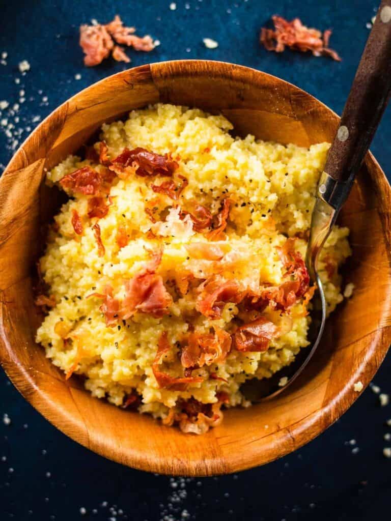 pastina with prosciutto in a wood bowl with a spoon.