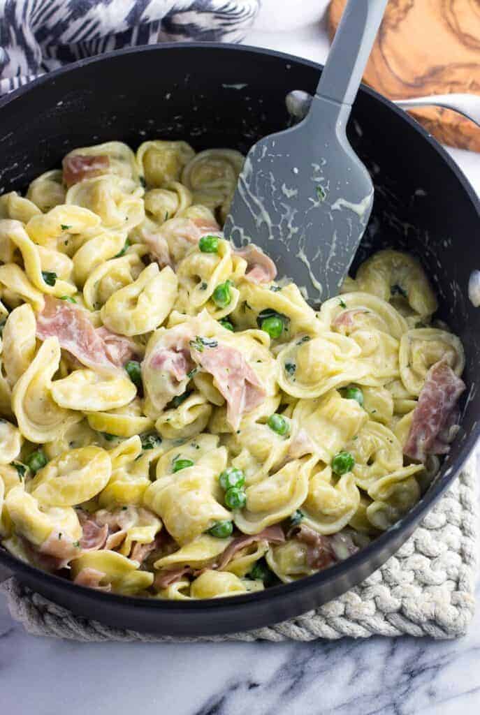 tortellini alla panna in a skillet with a spatula