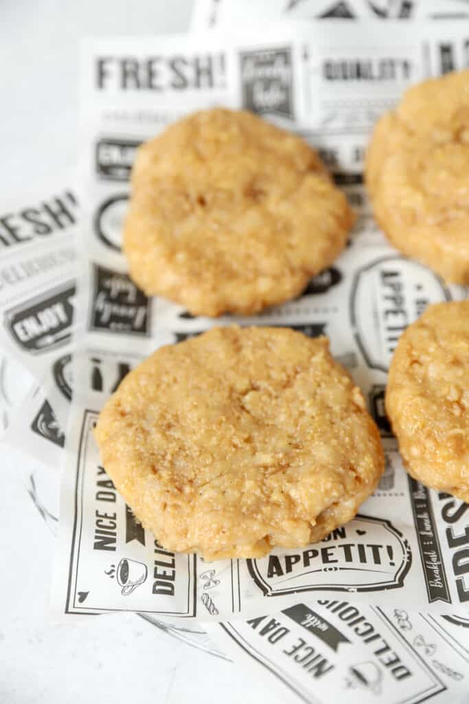 overhead photo of the raw chicken burgers on black and white printed food paper.