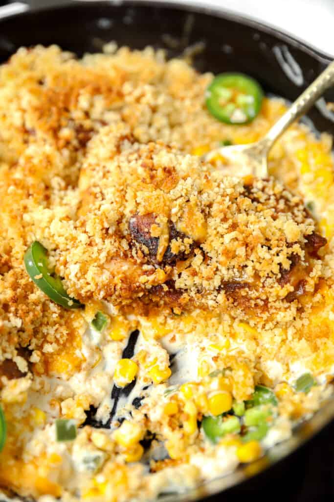 jalapeno popper chicken being scooped from a cast iron skillet.