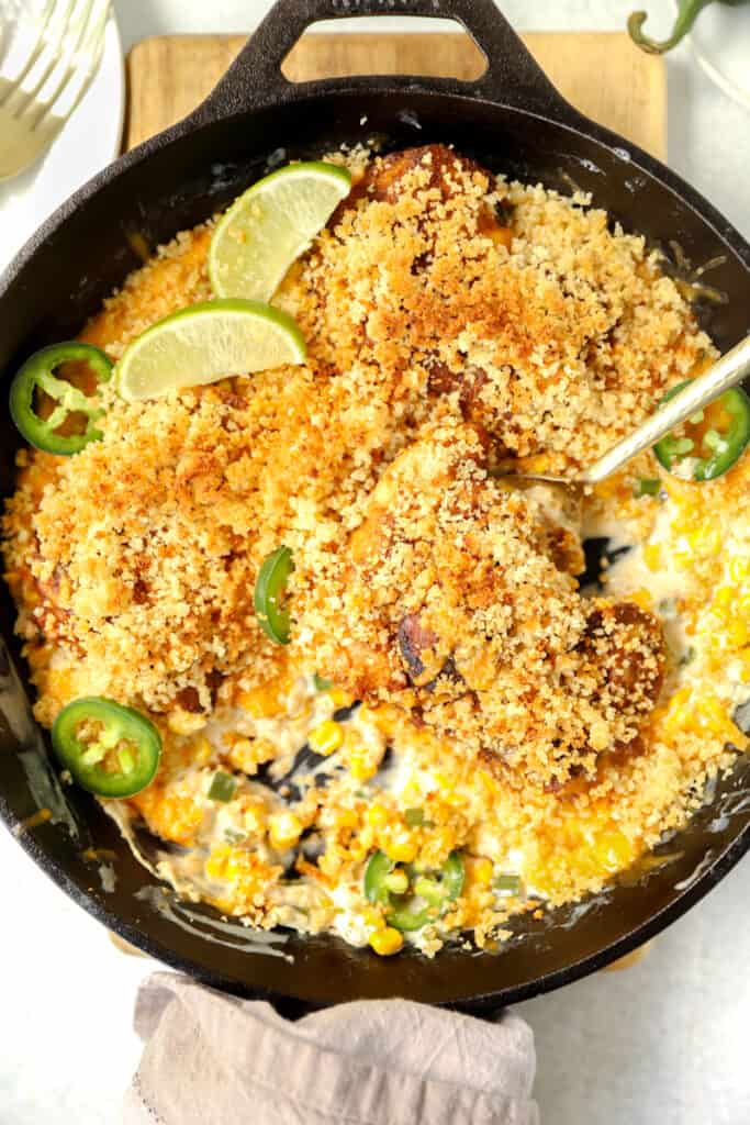 overhead photo of the jalapeno popper chicken in a cast iron skillet with a gold spoon.