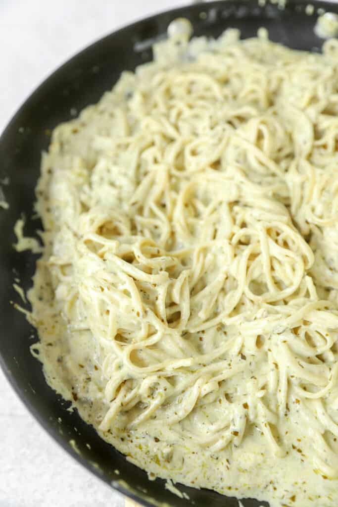 pesto alfredo in a black non-stick pan