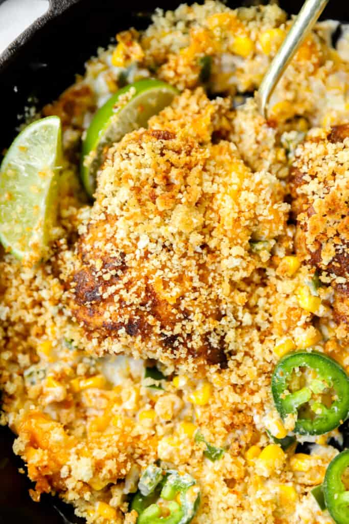 jalapeno popper chicken being scooped from a cast iron skillet.