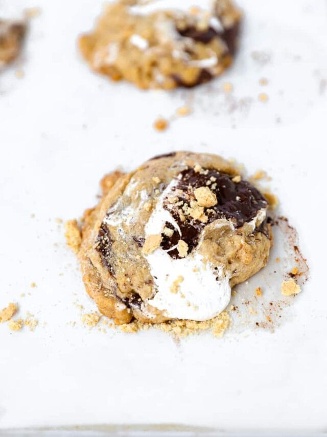 s'mores cookie topped with graham cracker crumbs on a parchment paper lined baking sheet
