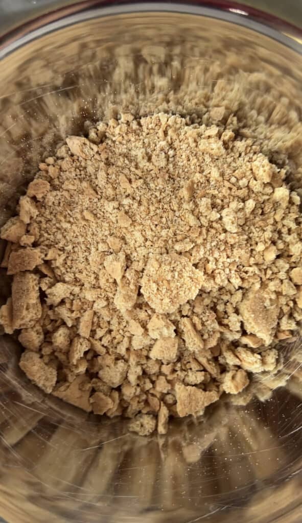 overhead photo of the crushed graham crackers in a silver mixing bowl.