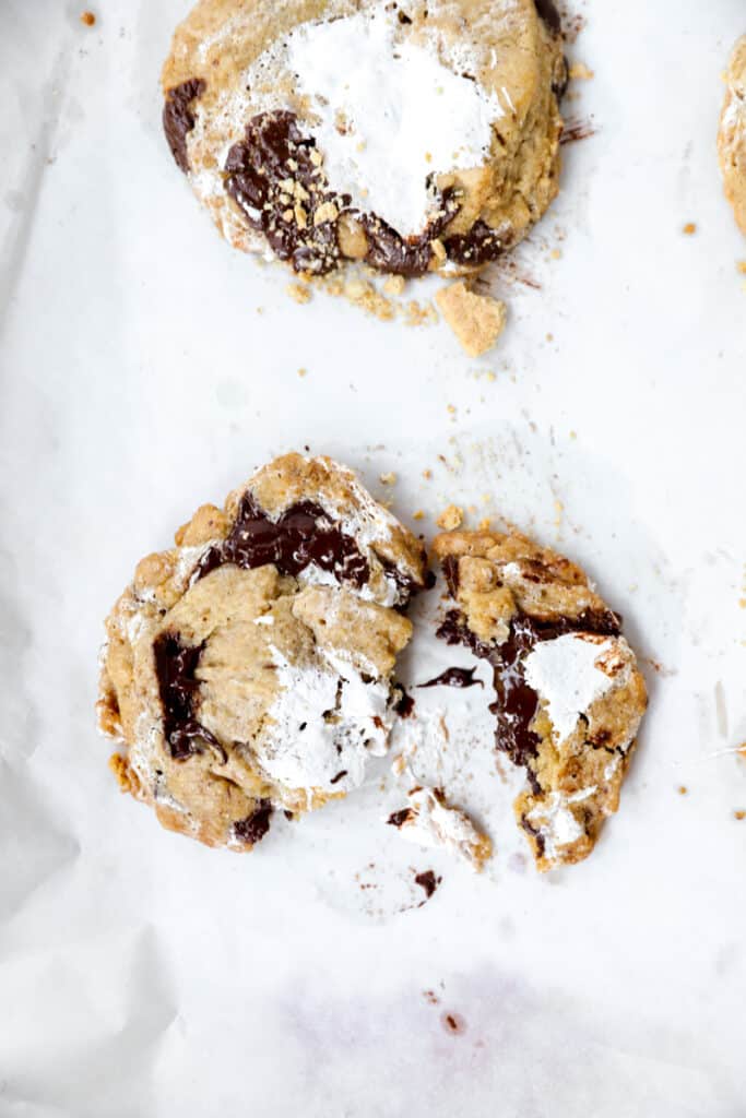 one of the cookies broken in half on a parchment paper lined baking sheet