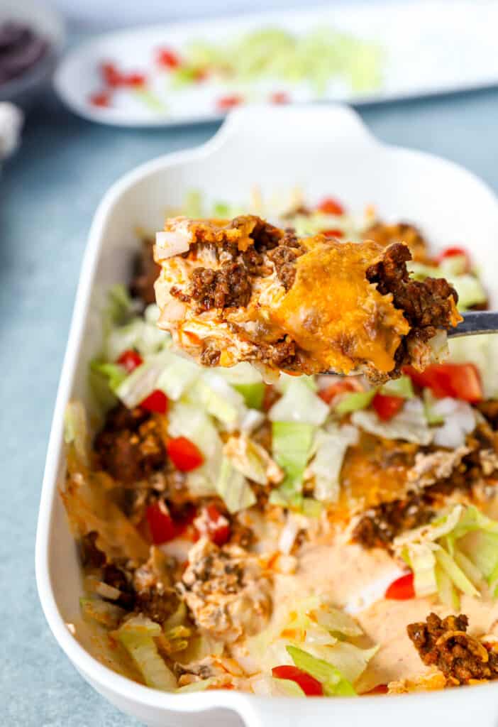 scooping the taco dip from the casserole dish