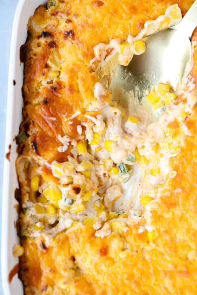 overhead photo of the Jalapeño corn dip in a white casserole dish with a gold spoon.