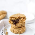 stack of 3 chocolate stuffed oatmeal cookies on round white plates.