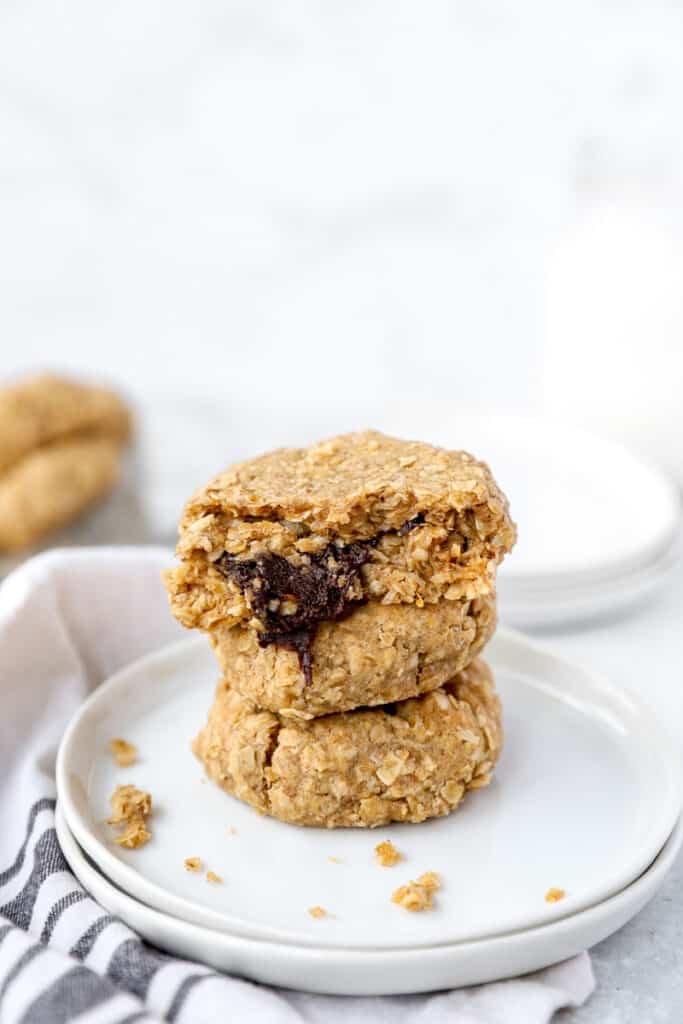 stack of 3 chocolate stuffed oatmeal cookies on round white plates.