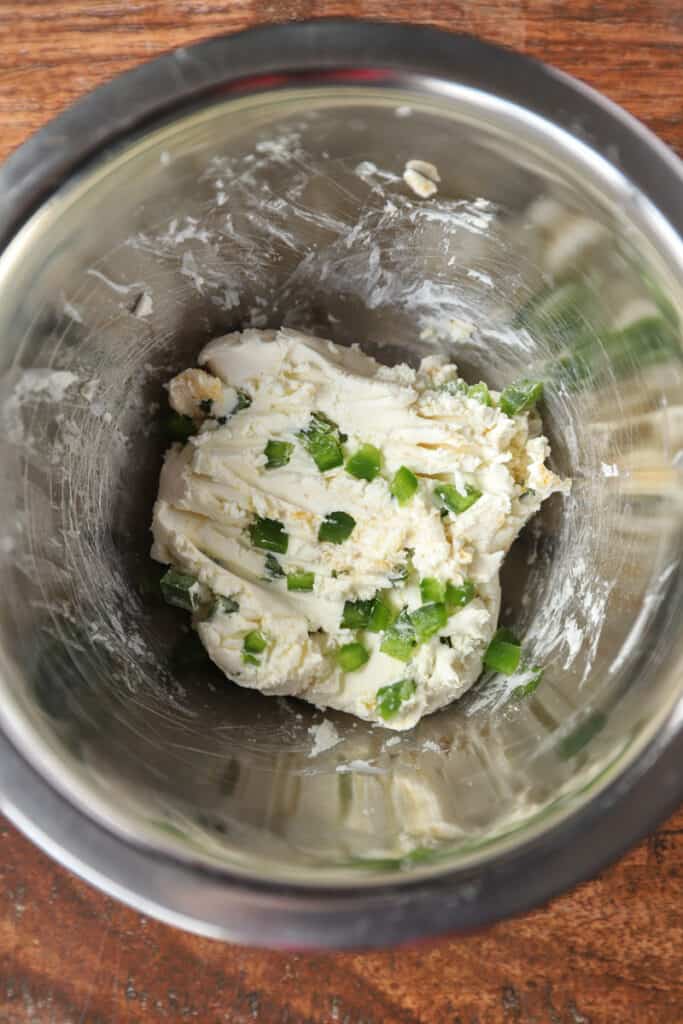 overhead photo of the jalapeno cream cheese blend in a stainless steel mixing bowl on a wood surface. 