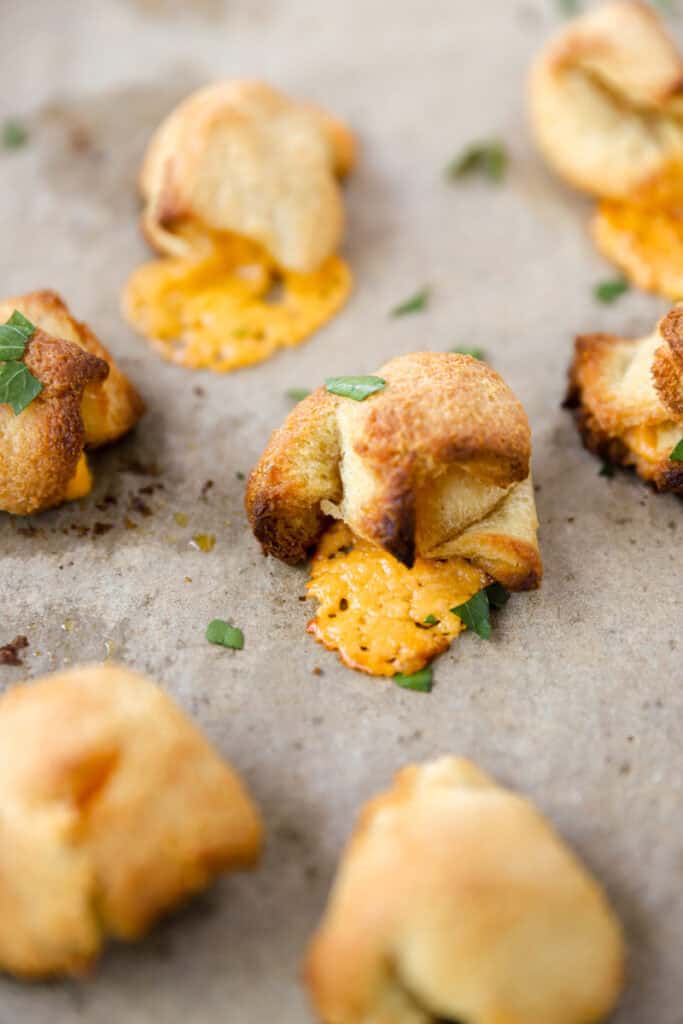 grilled cheese bites on brown parchment paper with chopped parsley. 